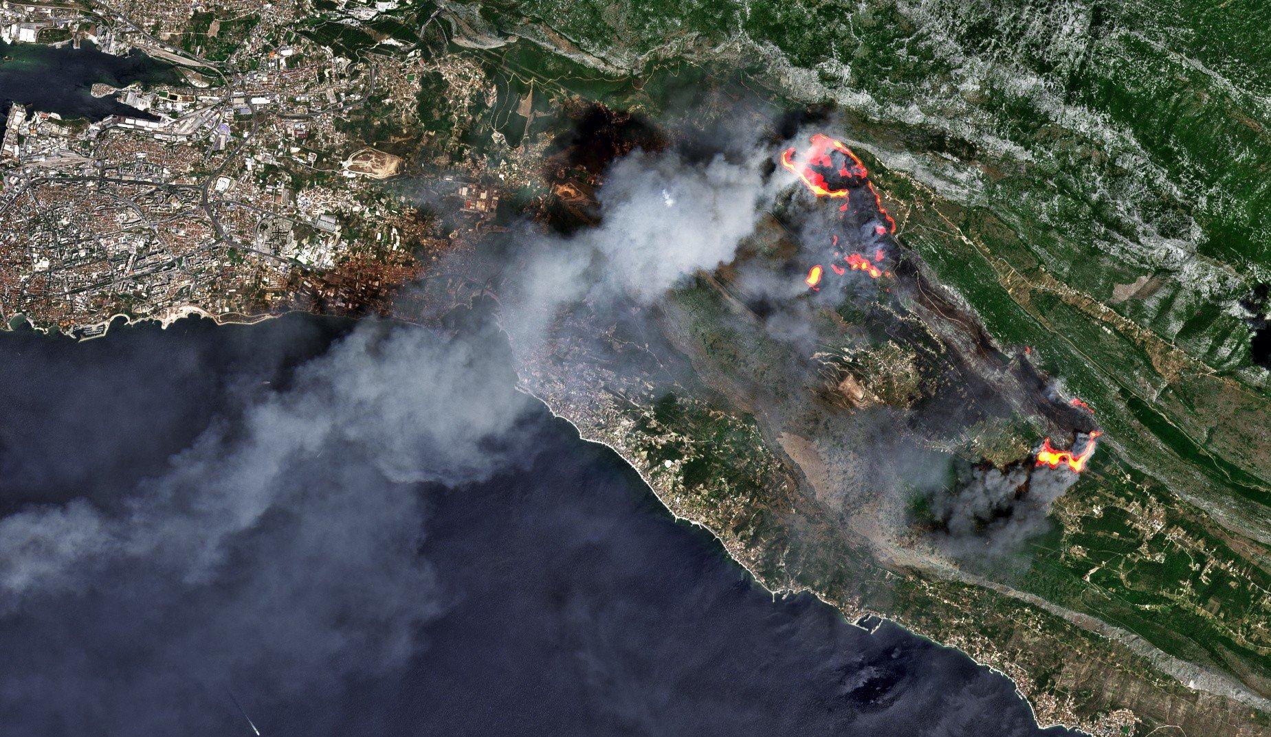 Imagen satelital de un incendio forestal costero, con varios frentes activos y densas columnas de humo.